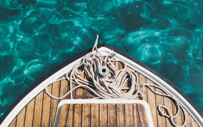 A top down view of the deck and front of a boat with coiled rope.